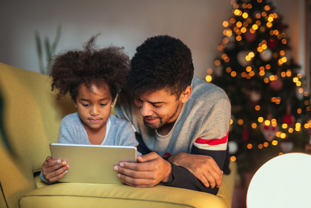 Dad and daughter watching holiday movie on tablet